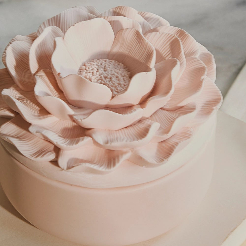 Pink flower-shaped jewelry box on a white plate with a marble background
