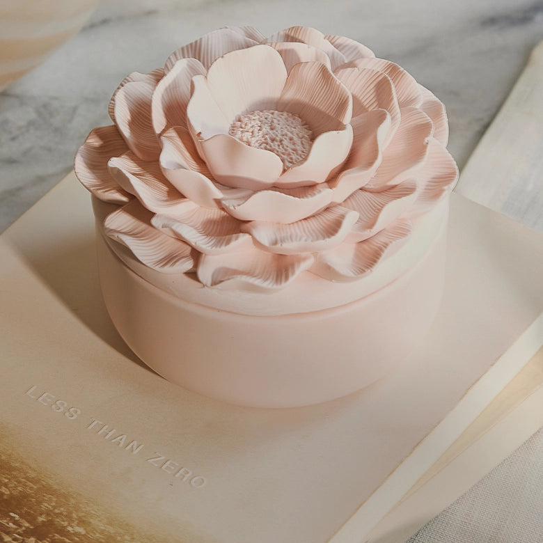 Pink flower-shaped container on an open book with a blurred background
