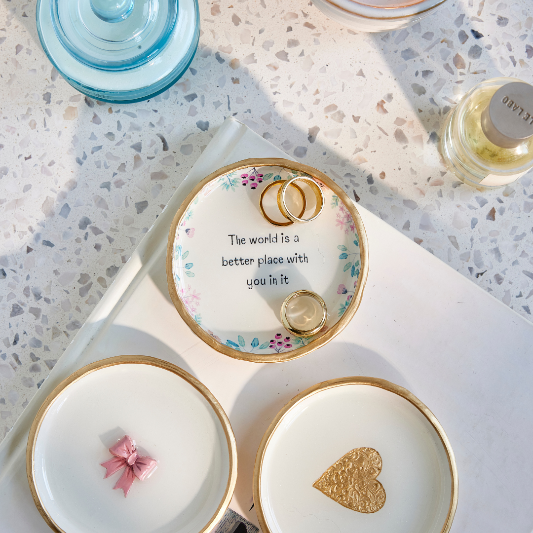 Set of decorative plates with floral, ring, and heart designs on a textured surface.