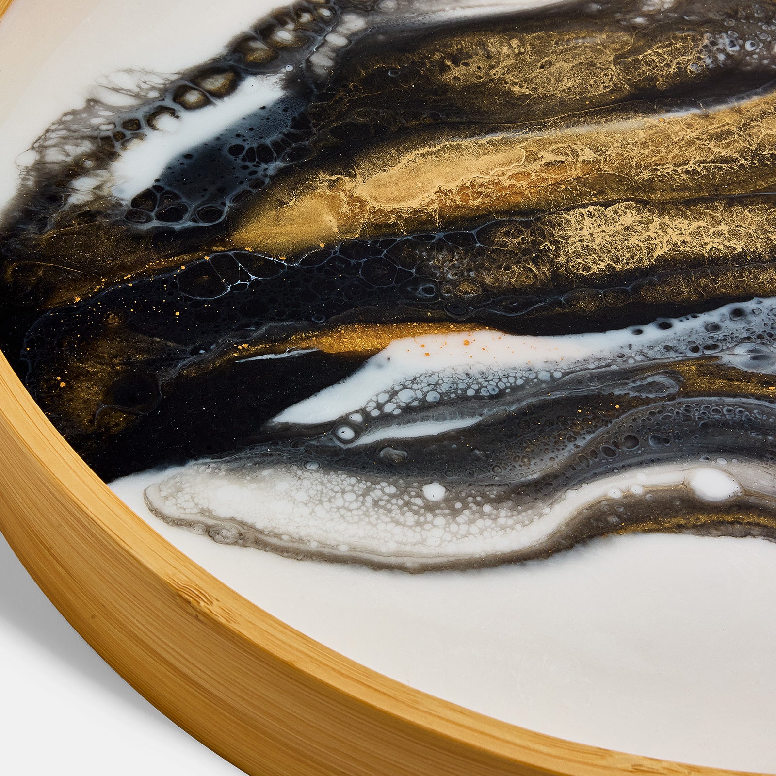 Close-up of a marbled art piece with gold, black, and white colors on a wooden frame.