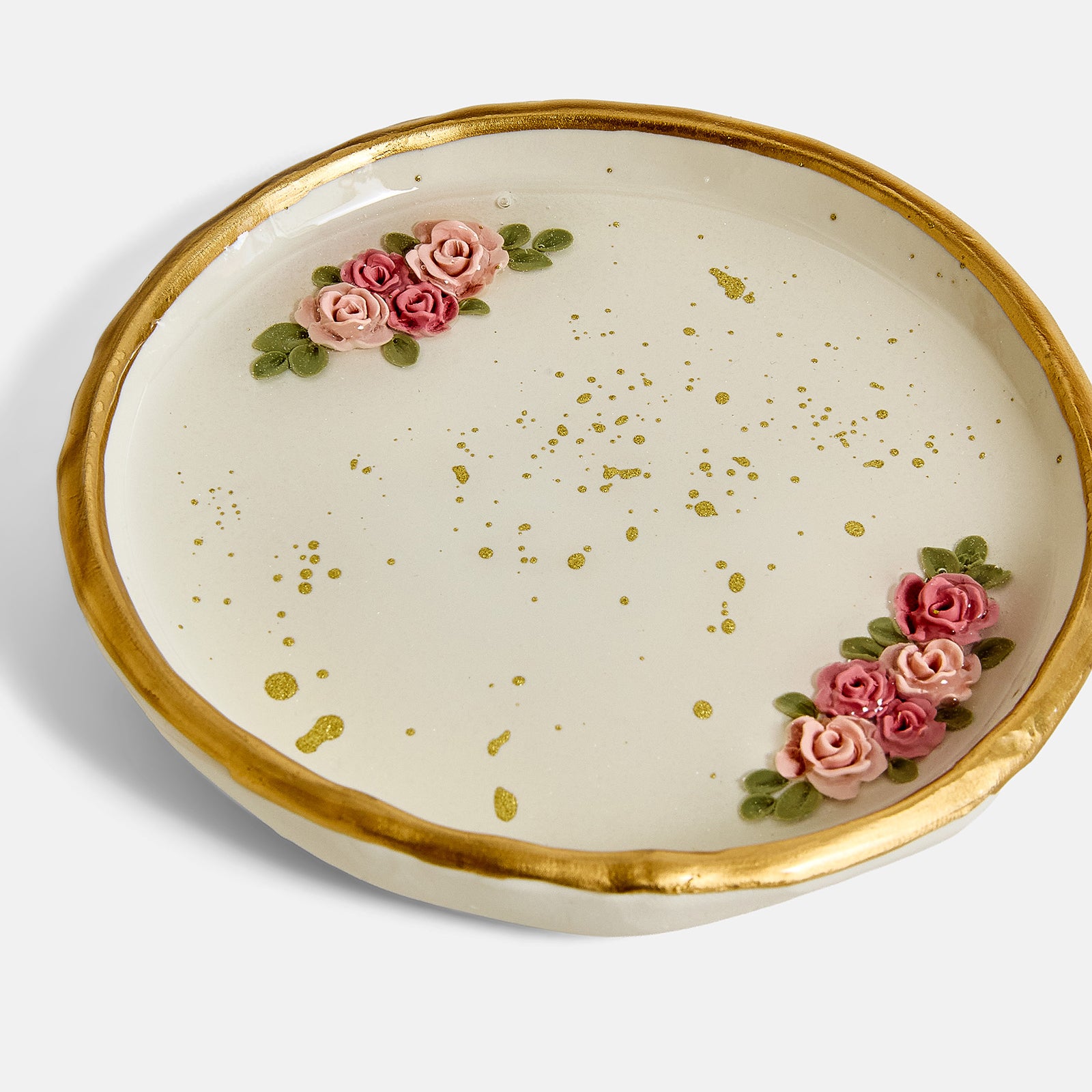 Ring dish with gold rim, pink roses, and gold speckles on a cream background