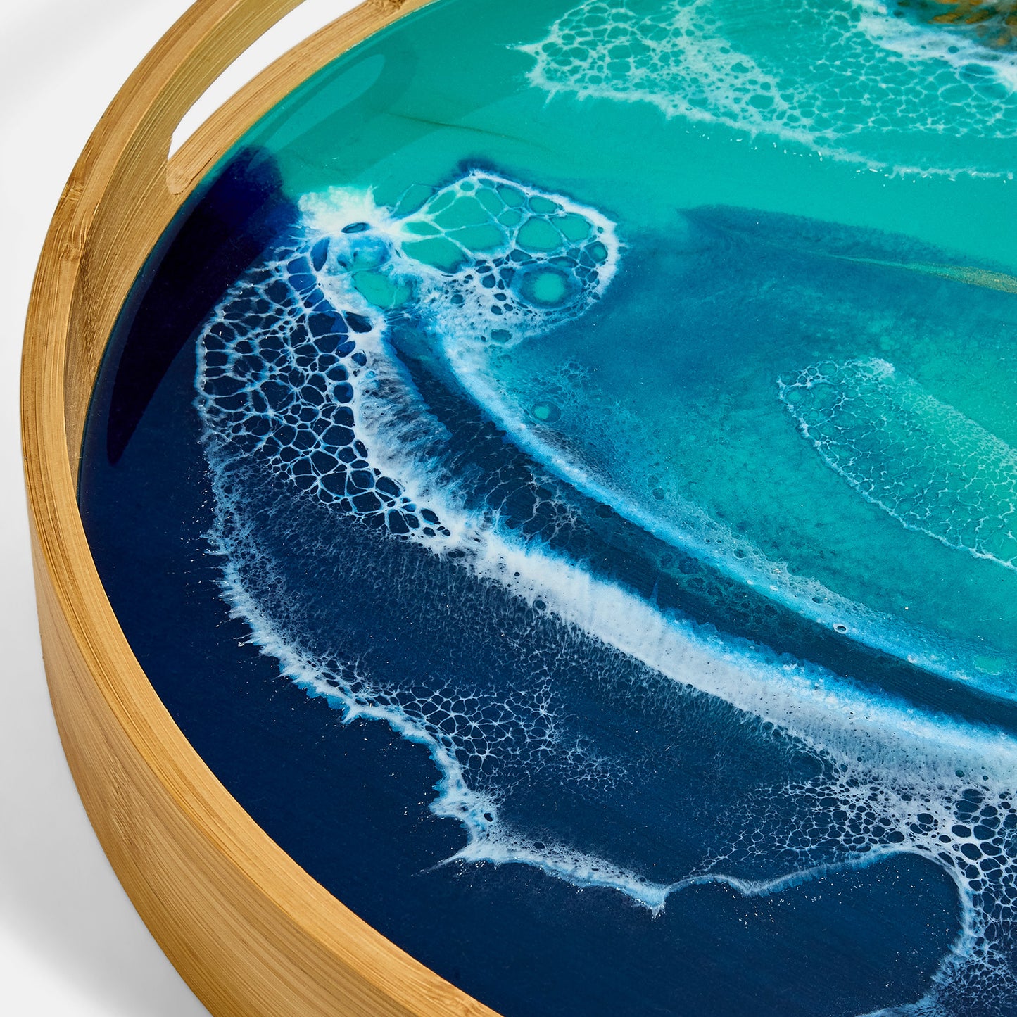 Round tray with a blue and turquoise ocean wave design on a wooden rim